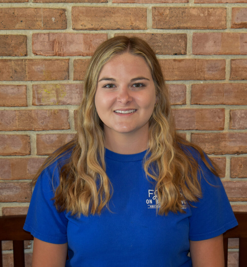 A woman in blue shirt sitting on top of a wooden bench.