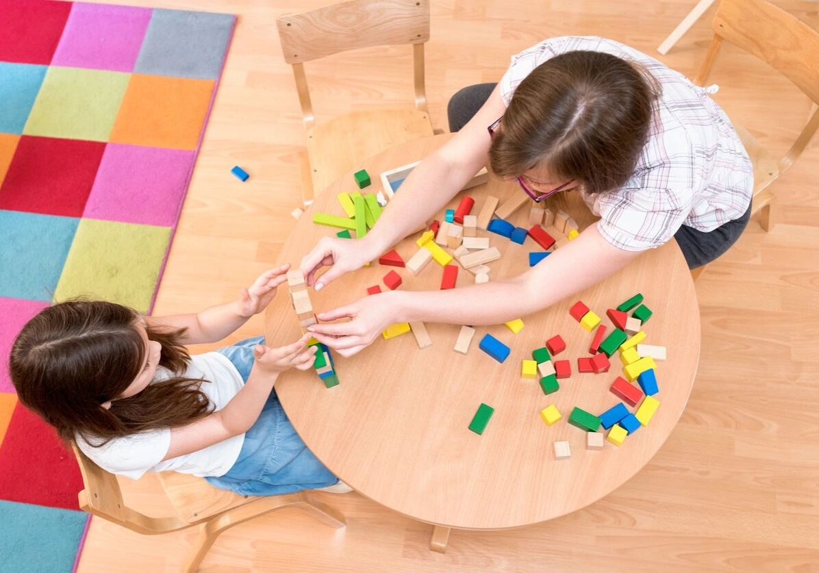 Two children playing with blocks on a table.